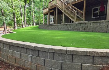 Artificial turf landscaping with retaining wall and elevated backyard deck