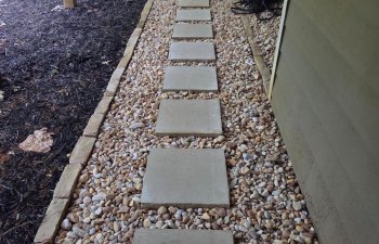 Stone pathway with decorative gravel landscaping beside backyard lawn